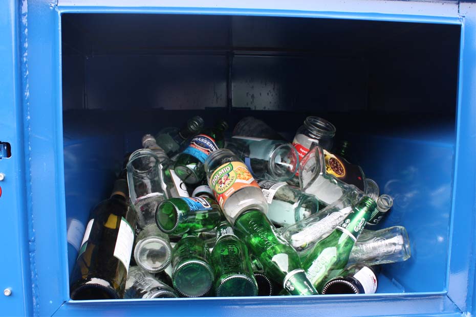 Empty glass bottles inside the loading chamber ready to be crushed.